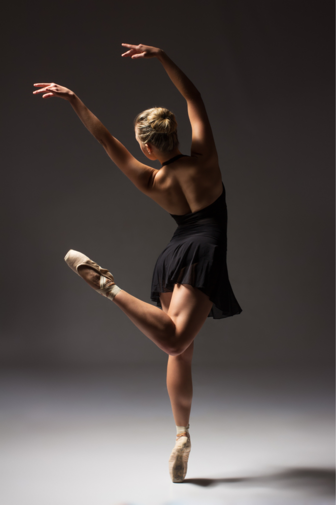 A photograph of a ballerina dancing, viewed from the back.